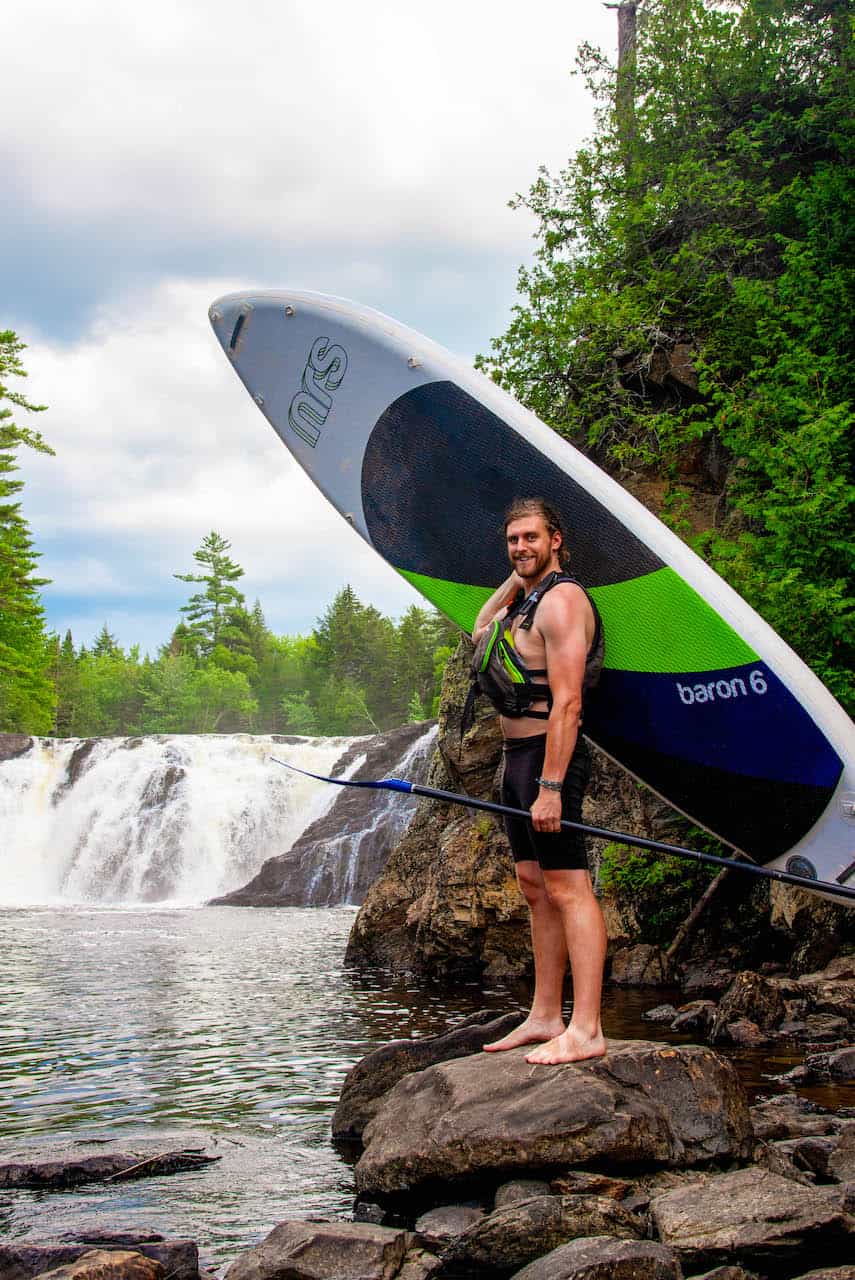 stand up paddleboarder with waterfall